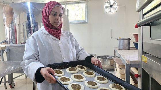 care-gaza-nisreen-praesentiert-gebaeck.jpg Nisreen präsentiert Gebäckstücke auf einem Blech.